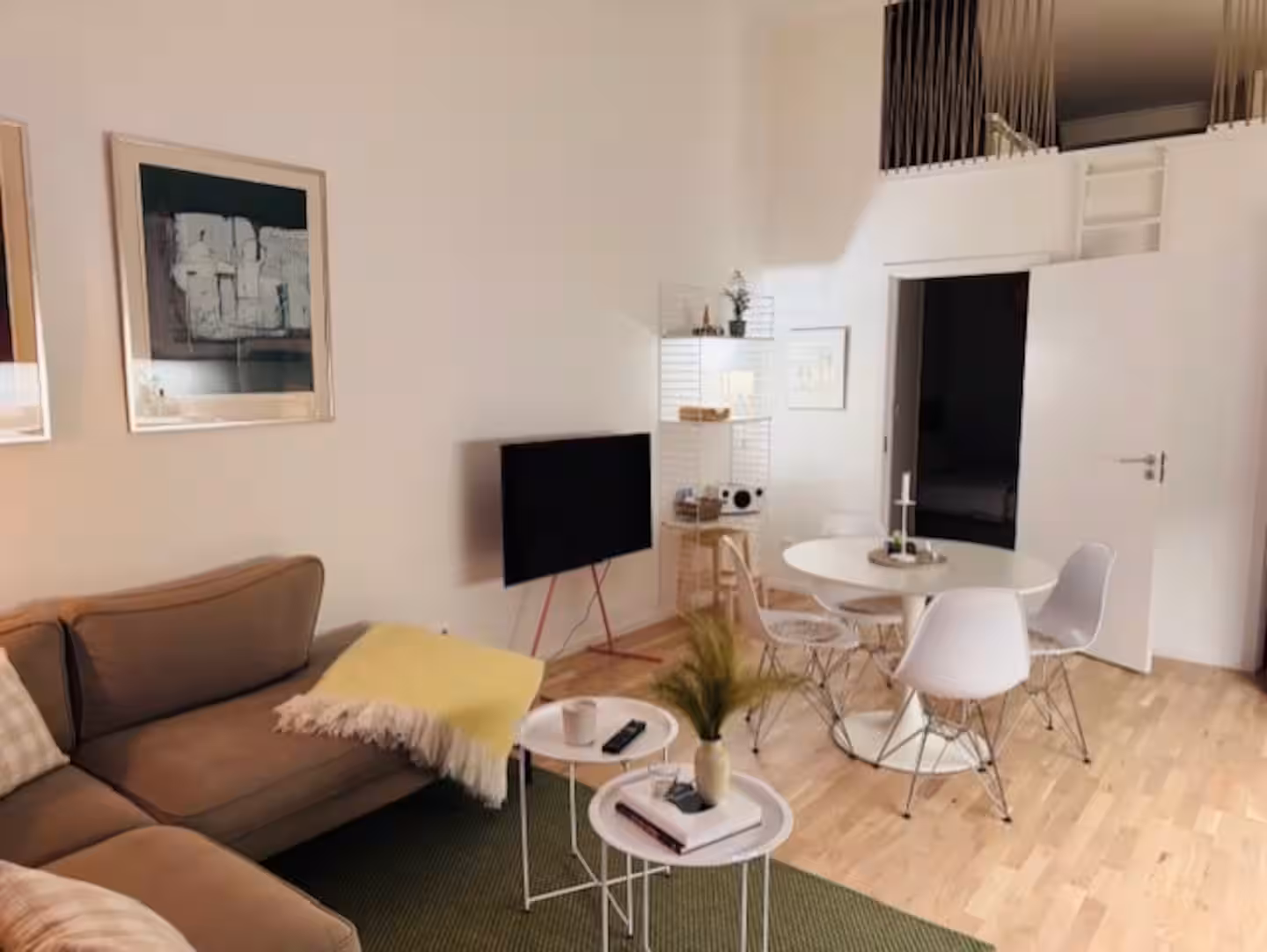Open-plan living room and dining area with high ceiling and sleeping loft